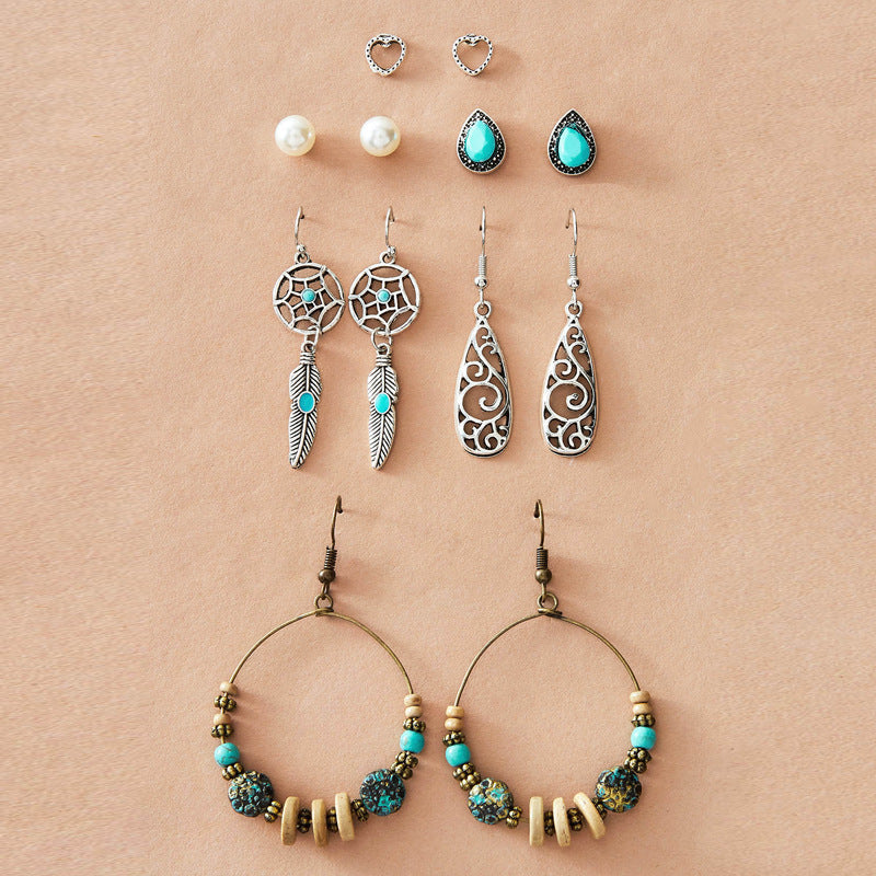 Collection of earrings including hoop, teardrop, and feather designs on a beige background