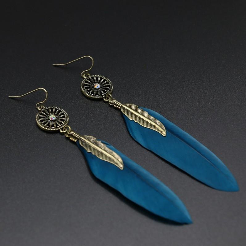 Blue feather earrings with gold accents on a dark background