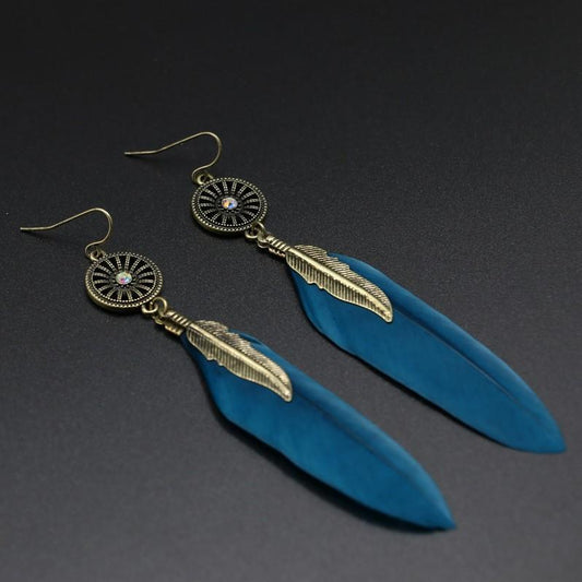 Blue feather earrings with gold accents on a dark background