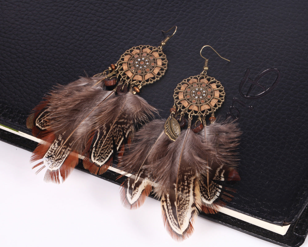 Feathered earrings with intricate designs on a black background