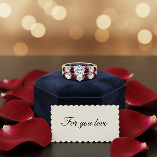Silver ring with red gemstones and clear stones on a blue box with red rose pedals