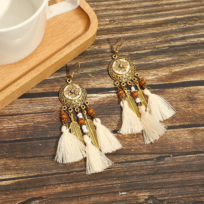 Ornate gold earrings with tassels on a wooden surface