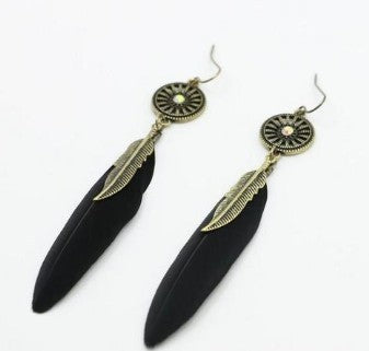 Black feather-shaped earrings with gold accents on a white background