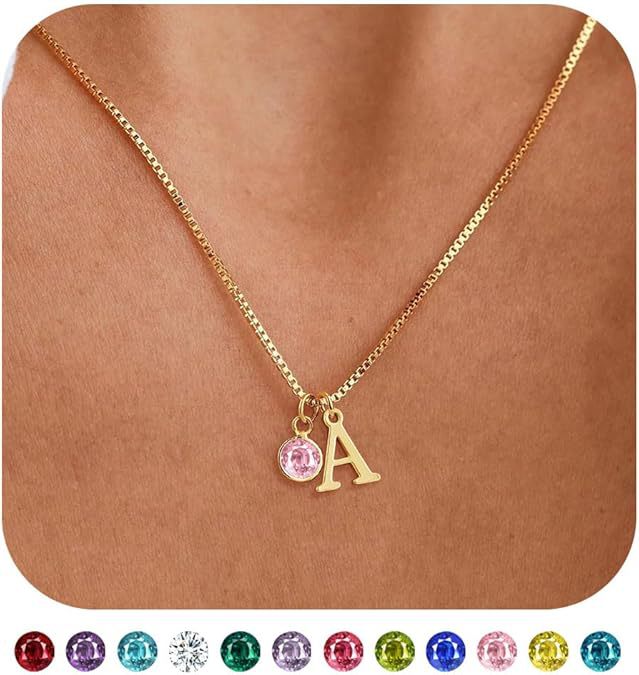 Gold necklace with a pink gemstone and letter 'A' pendant on a brown background.
