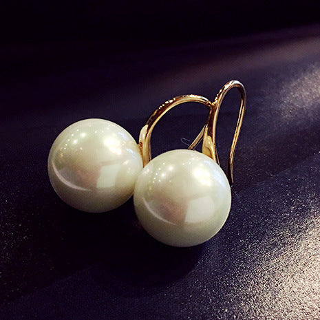 Pearl earrings with gold hooks on a dark surface
