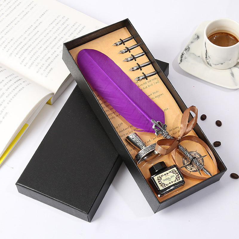 Feather quill pen set with ink bottle and tools in a black box on a white surface.