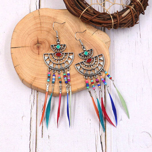 Colorful earrings with feathers on a wooden board