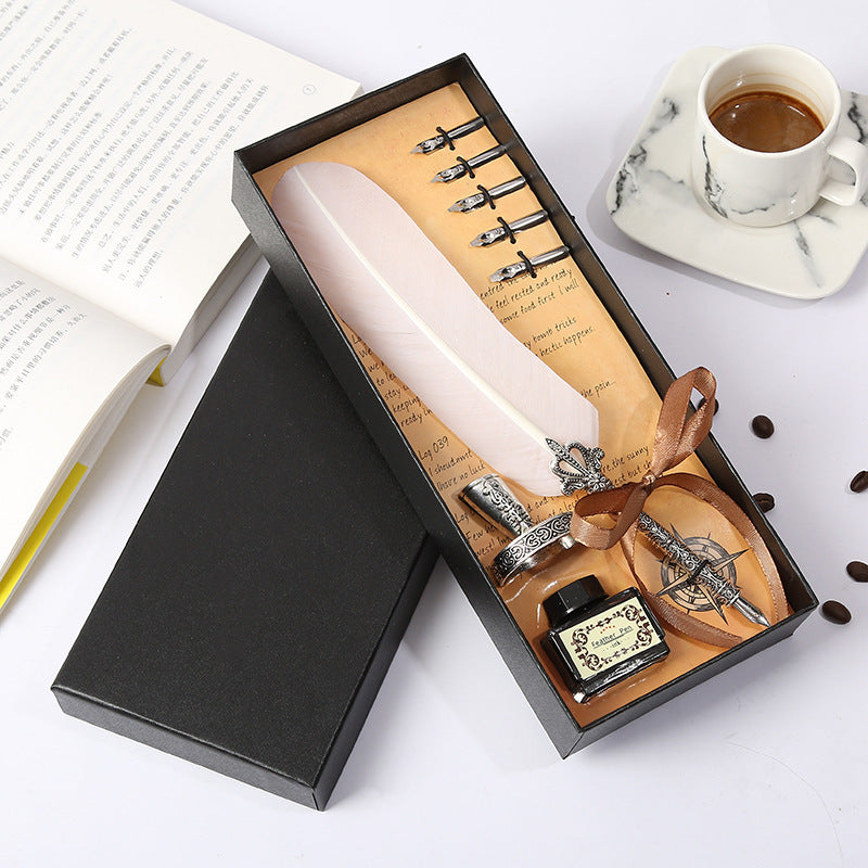 Calligraphy set with a feather pen, ink bottle, and nibs in a black box on a white surface.