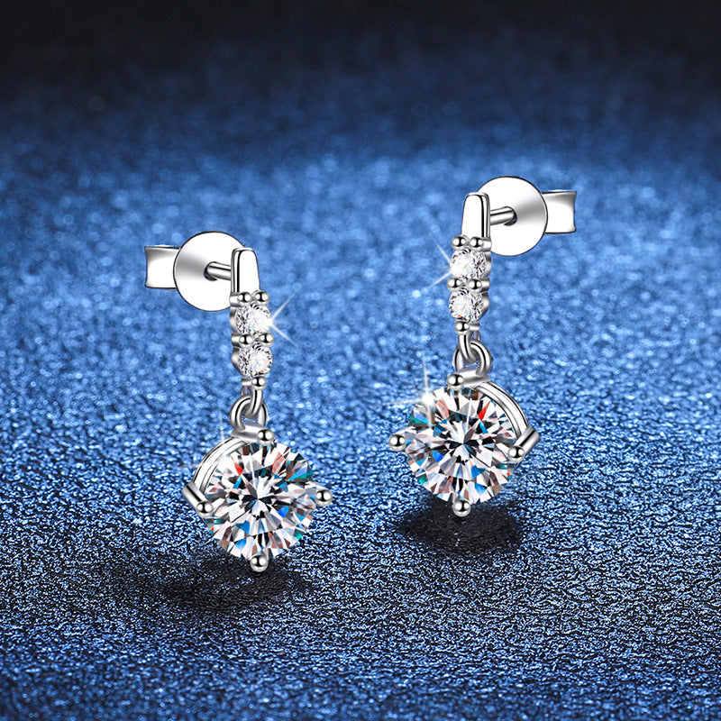 Silver earrings with clear gemstones on a blue textured background