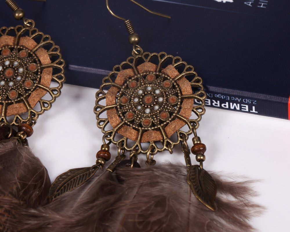 Ornate earrings with feather details on a white surface