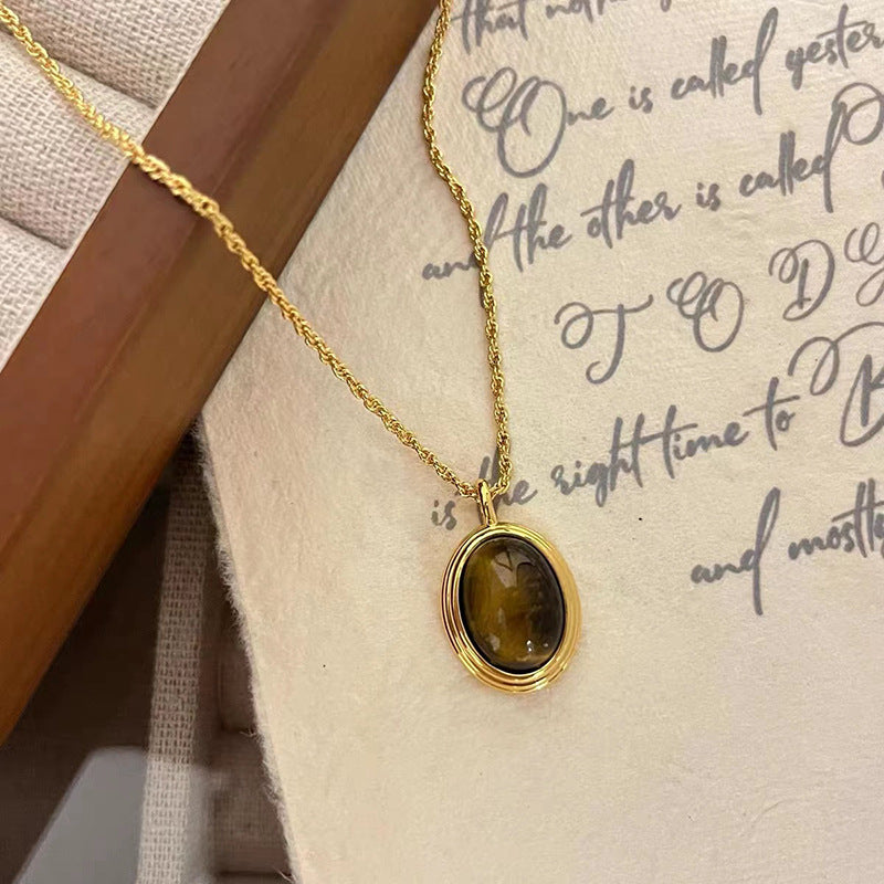 Gold necklace with a brown pendant on a textured surface with text