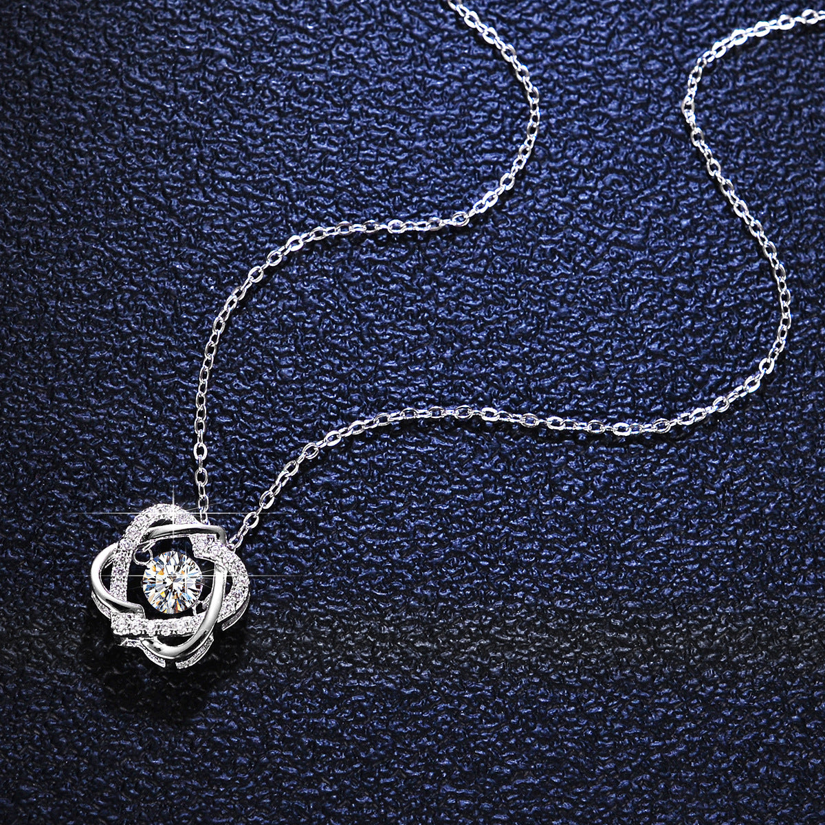 Silver necklace with a floral pendant on a dark blue textured background