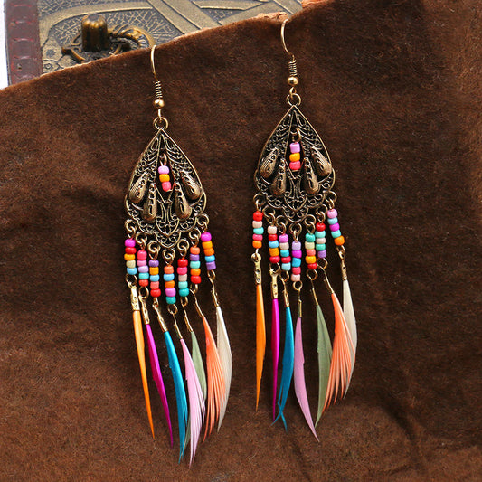 Colorful feather earrings with intricate designs on a brown background