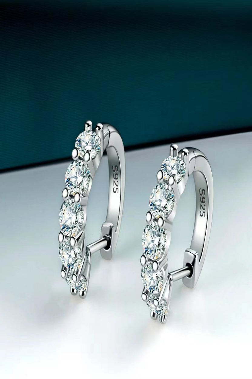 Pair of silver hoop earrings with clear gemstones on a gradient background