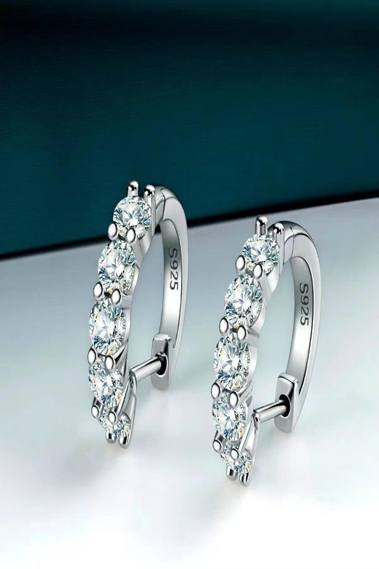 Pair of silver hoop earrings with clear gemstones on a gradient background