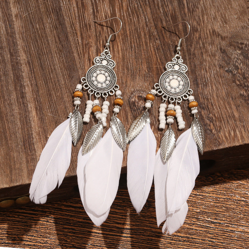 Feathered earrings with silver and white design on a wooden background