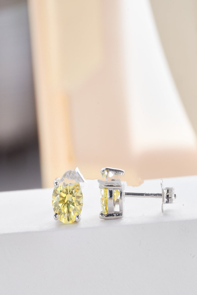 Pair of yellow gemstone stud earrings on a white surface with a soft blurred background
