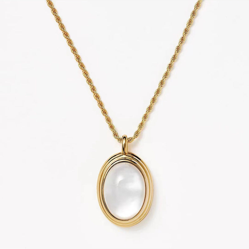 Gold necklace with a white pendant on a white background