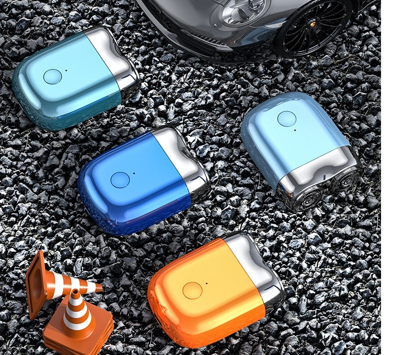 Four car air fresheners in blue and orange on a gravel surface with a car in the background.