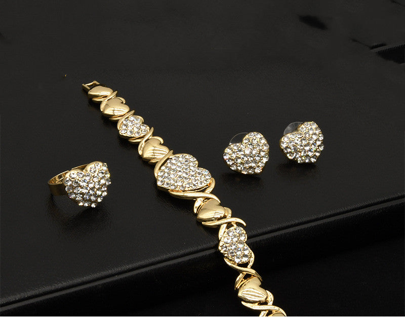 Gold jewelry set with bracelet, ring, and earrings on a black background