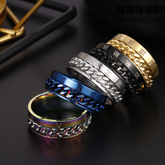 Four metallic rings with chain designs and Roman numeral accents on a dark surface.