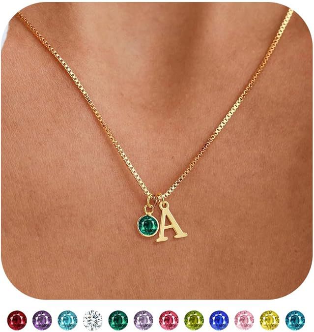 Gold necklace with a green gemstone and letter 'A' pendant on a brown background.
