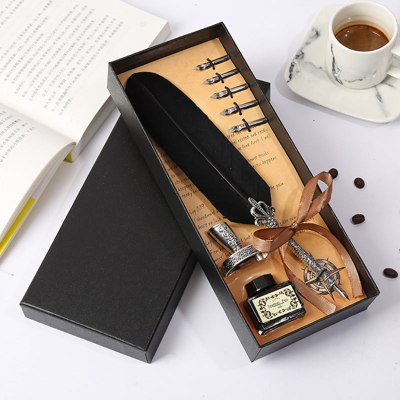 Fountain pen set with ink bottle and nibs in a black box on a white surface.