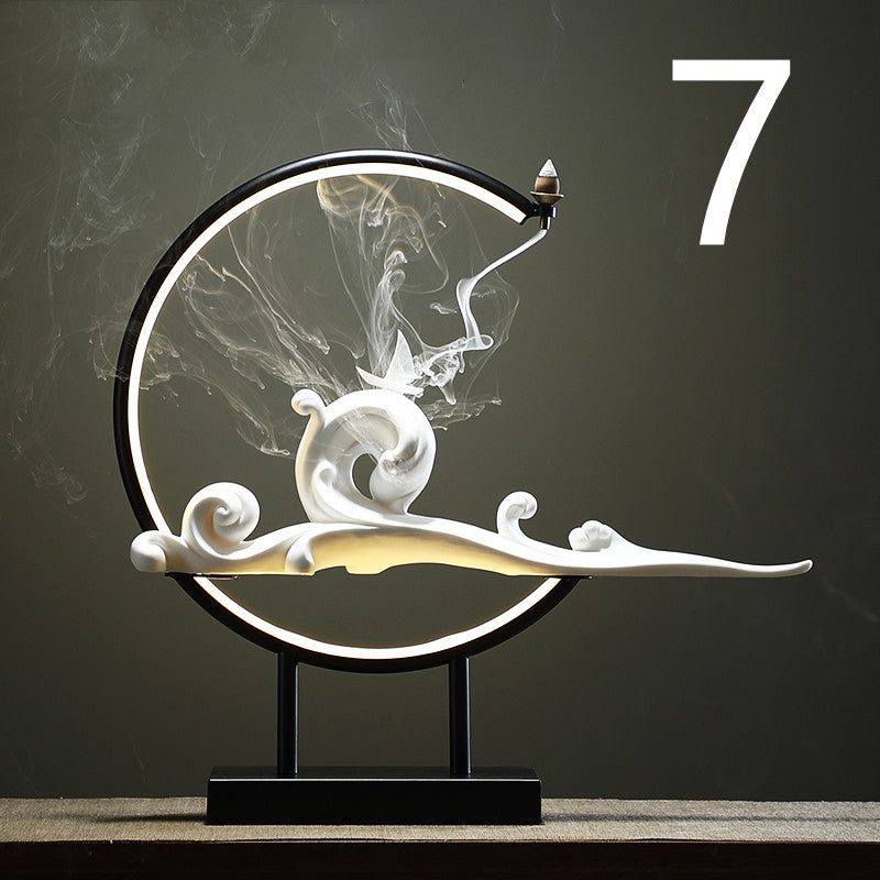 Decorative sculpture of a snail on a crescent moon with incense against a dark background.