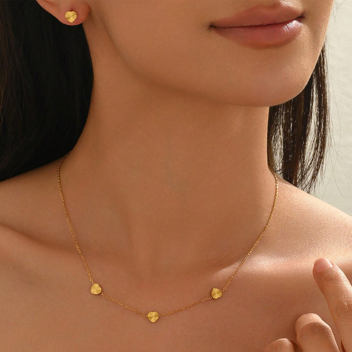 Gold necklace with heart-shaped pendants worn by a person
