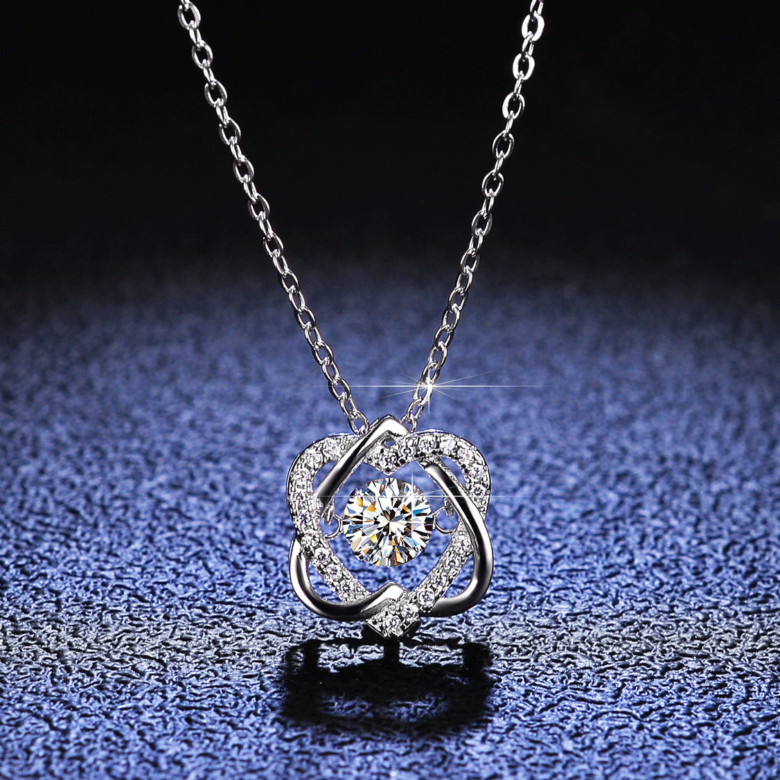 Silver necklace with a heart-shaped pendant on a dark textured surface