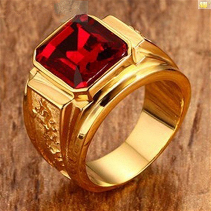 Gold ring with a red gemstone on a wooden background