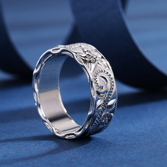 Silver ring with intricate designs on a blue background