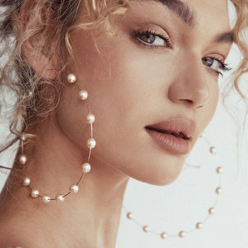 Close-up of a woman wearing pearl earrings with a soft focus background