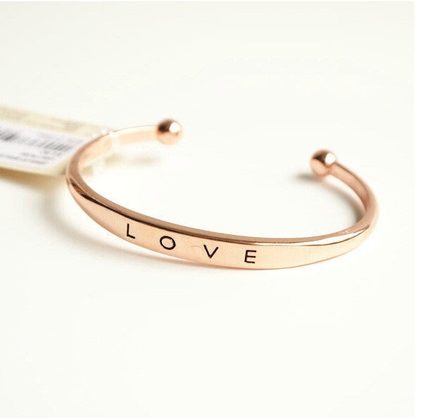 Rose gold bracelet with 'LOVE' engraving on a white background