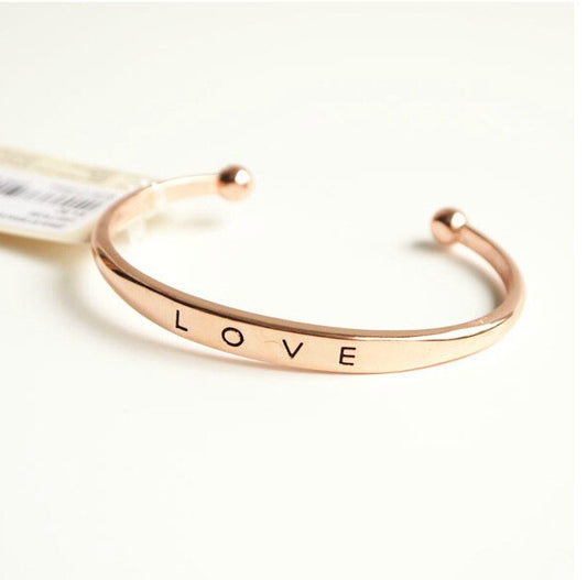 Rose gold bracelet with 'LOVE' engraving on a white background