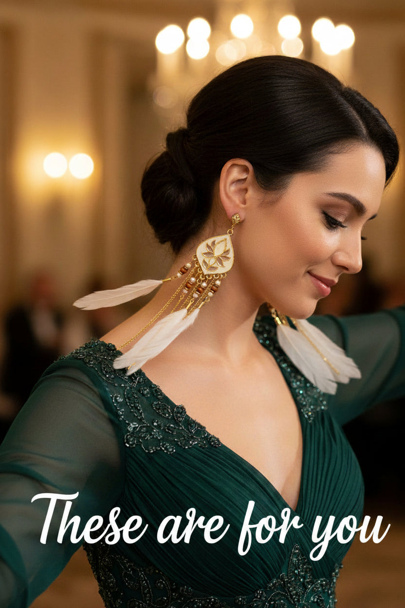 Pair of earrings with white feathers, gold chains, and decorative elements on a woman dancing