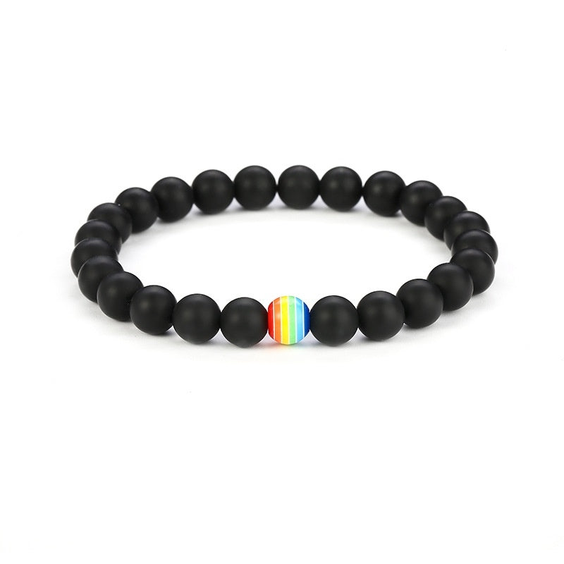 Black beaded bracelet with a rainbow center bead on a white background