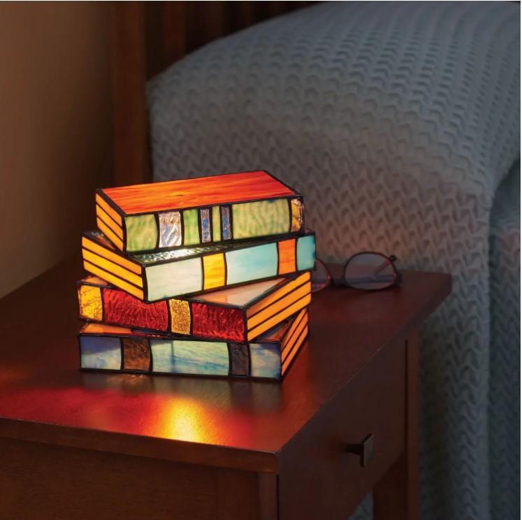 A colorful book-shaped accent lamp on a bedside nightstand