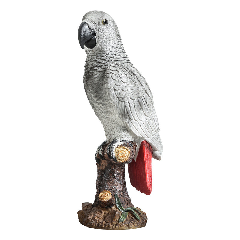 Gray parrot figurine on a branch with a red object, white background
