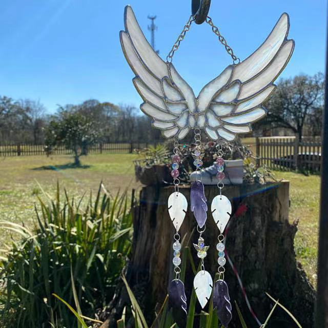 Decorative angel wing sun catcher with beads hanging outdoors.