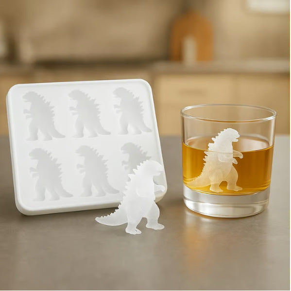 Silicone mold with dinosaur shapes next to a glass of amber liquid on a neutral background