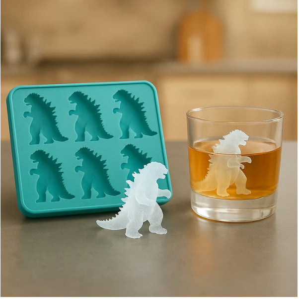 Silicone mold shaped like Godzilla next to a glass with a Godzilla ice cube in a drink.