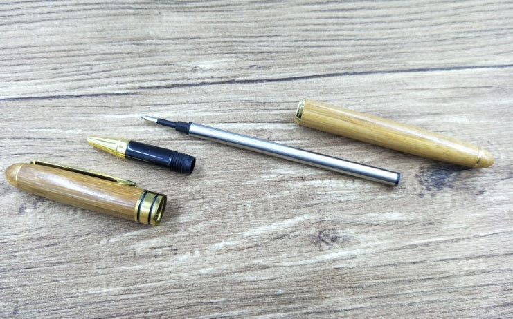 “Set of bamboo pens and ink refills arranged on desk surface”