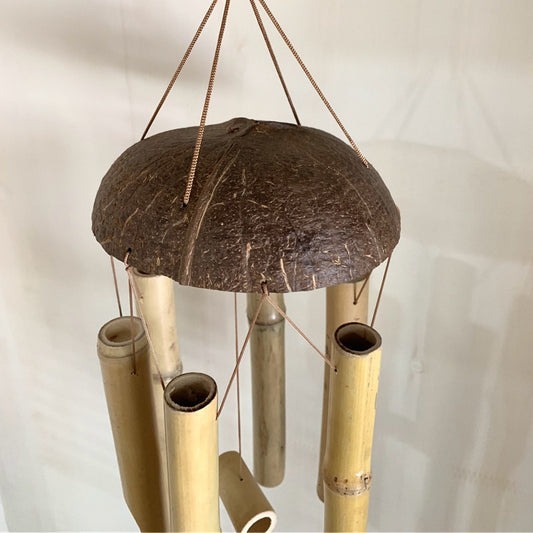 Bamboo wind chime with a coconut shell on a plain background