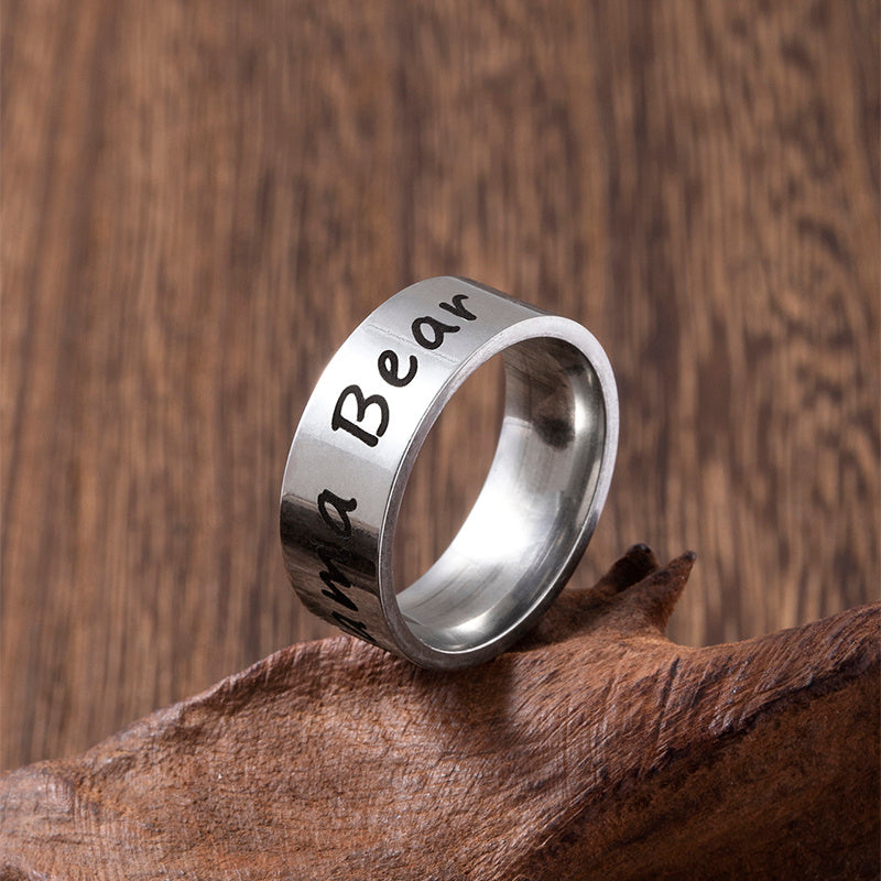 Silver ring with engraved text on a wooden surface