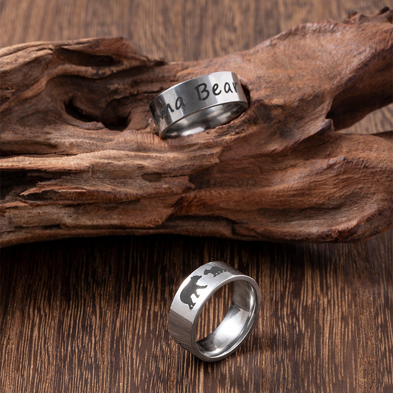 Two silver rings with engraved designs on a wooden surface