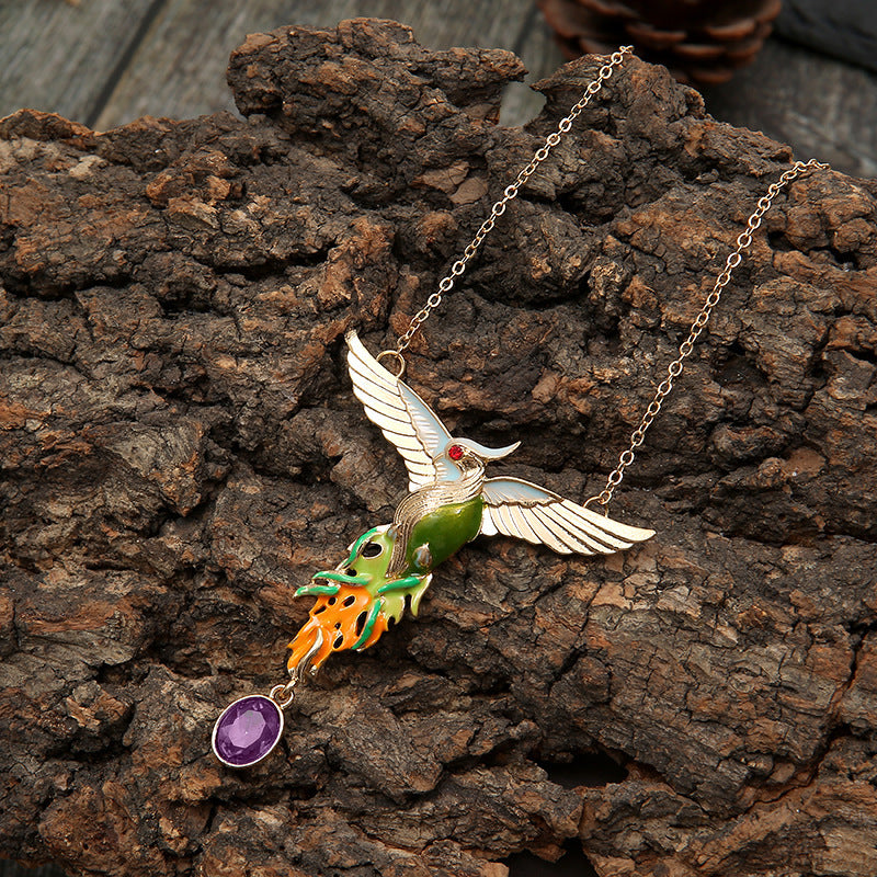 Bird-shaped necklace with a purple pendant on a wooden surface