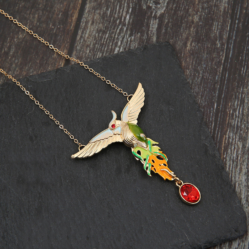 Hummingbird-shaped necklace with gemstones on a dark stone surface