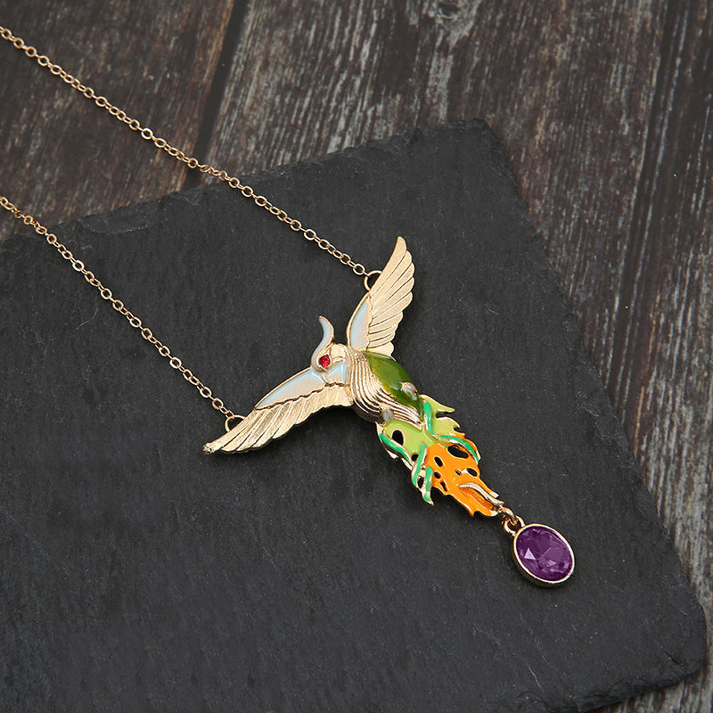 Colorful hummingbird-shaped pendant necklace on a dark stone surface
