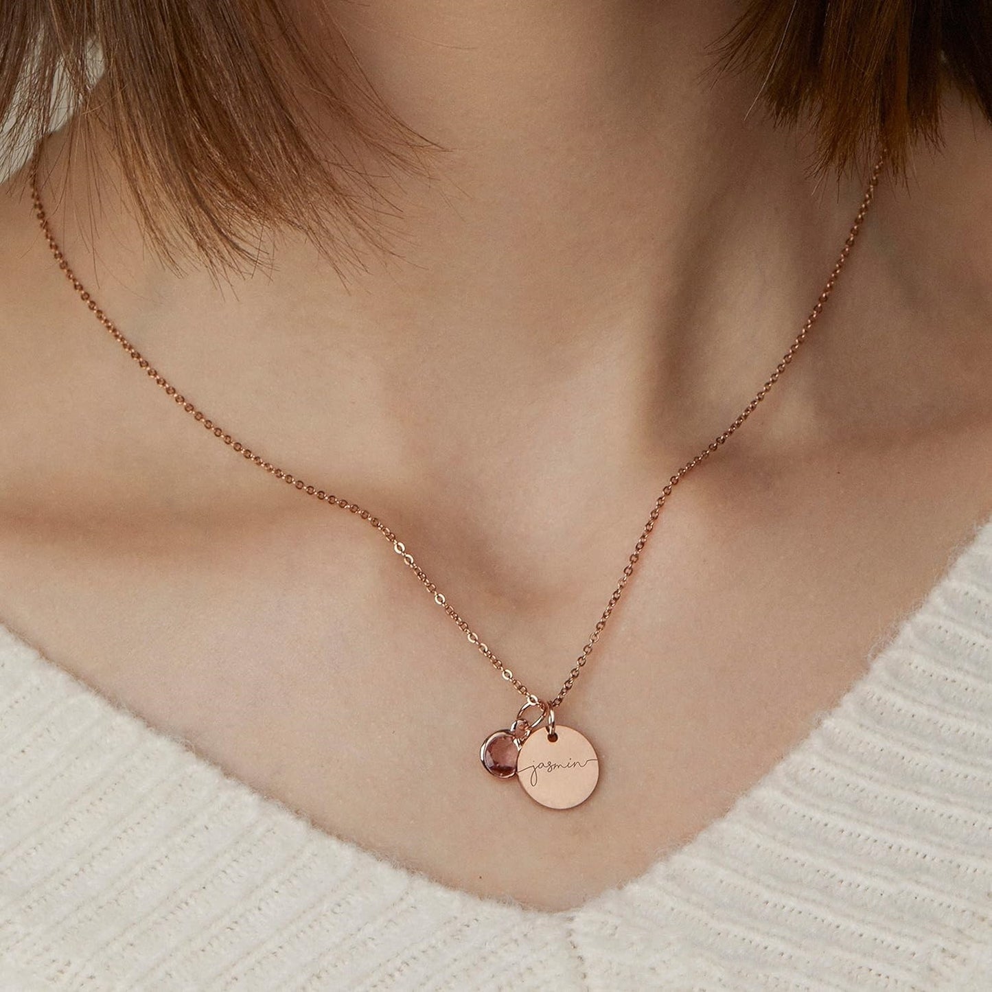 Rose gold necklace with circular pendants on a person wearing a white sweater.